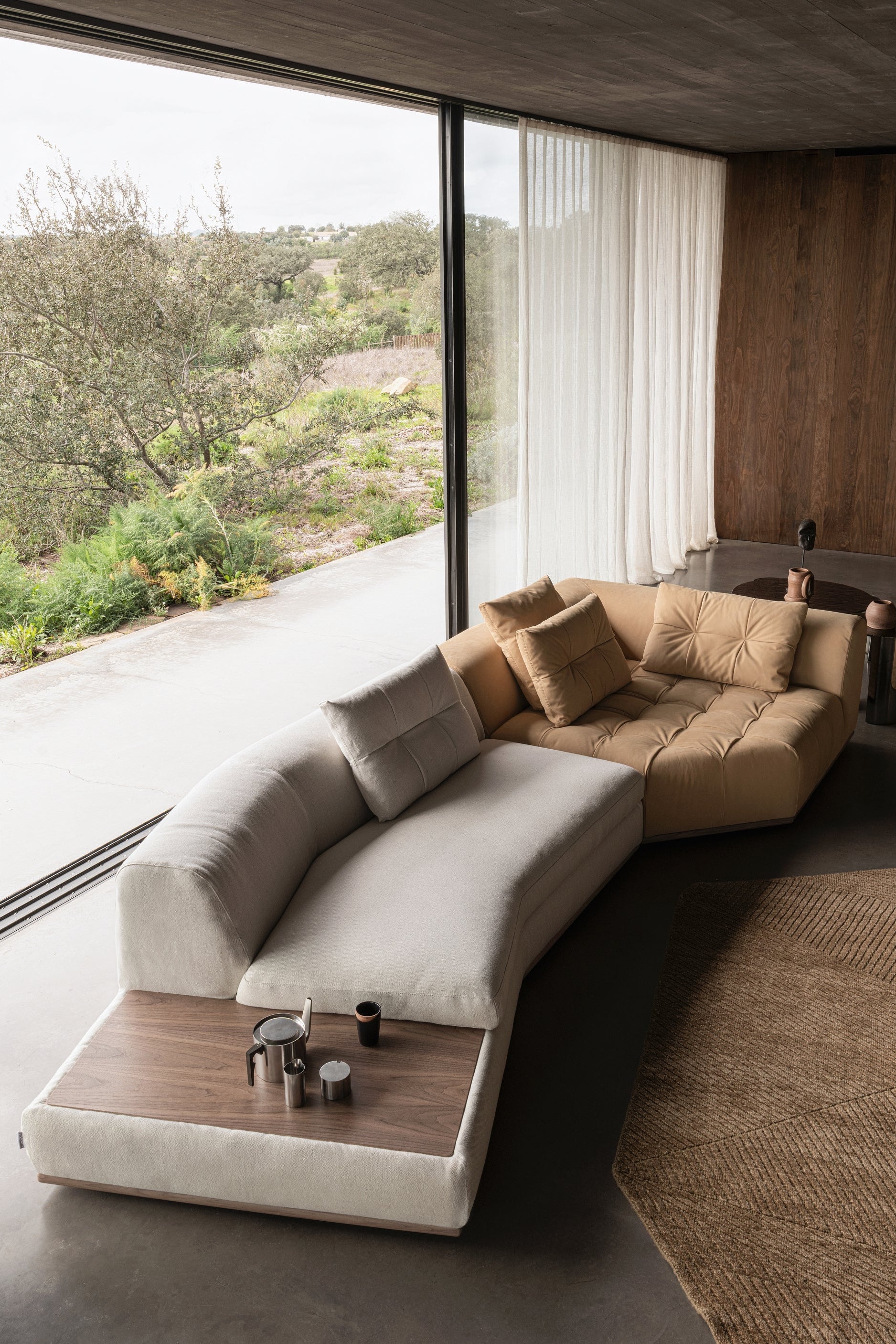 Modern living room with a curved sectional sofa and large windows.